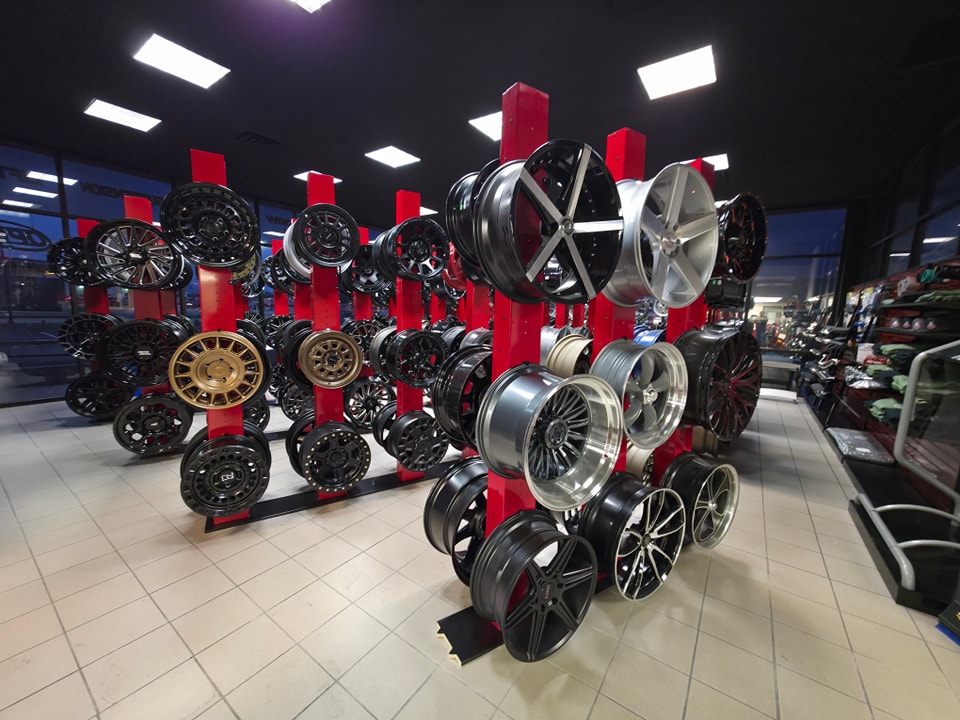 A showroom displaying a variety of wheels mounted on vertical red racks.