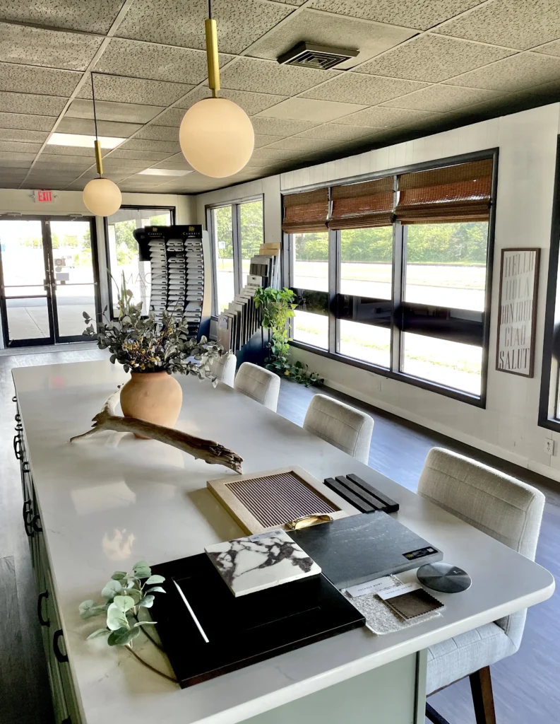 A modern design studio featuring a large white island table topped with design samples, floral arrangements and decor.